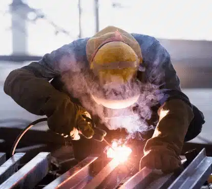 Welder in protective helmet MIG welding a steel frame in Illinois