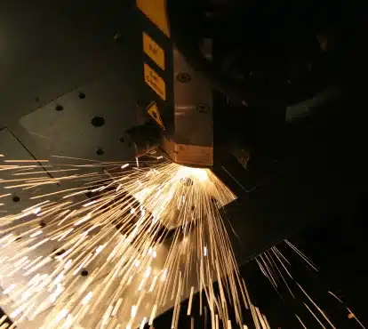 CNC laser cutting head cutting metal with a spray of sparks in Illinois