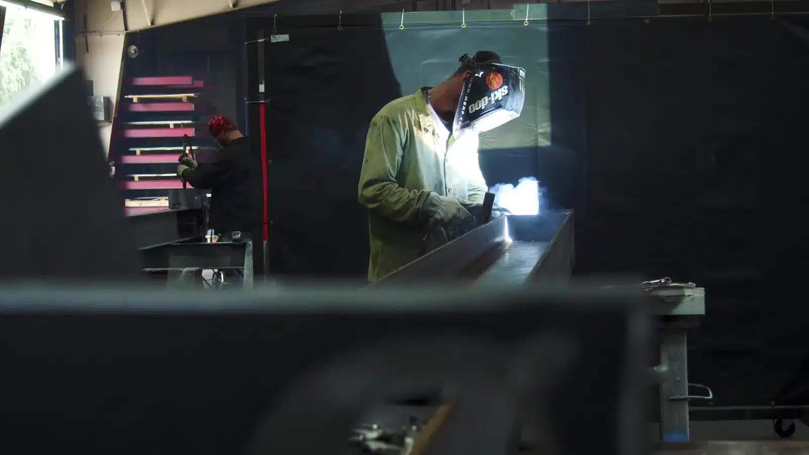 Fabricator welding a steel part inside the Versatile Fabrication shop in Michigan
