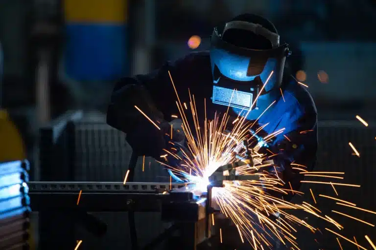 Welder in a protective helmet welding steel with sparks flying in Michigan
