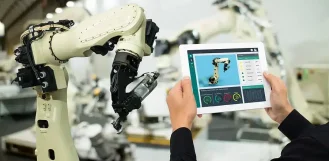 Technician controlling an industrial robot arm from a tablet - automation fabrication in Illinois