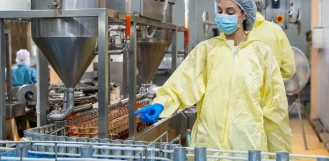 Worker in protective gear inspecting a stainless steel food processing line in Illinois