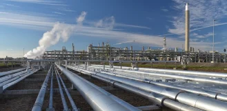 Pipelines running toward an oil and gas refinery under a blue sky in Illinois