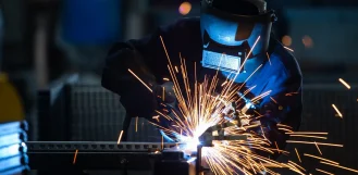 Welder in a protective helmet welding steel with sparks flying in Illinois
